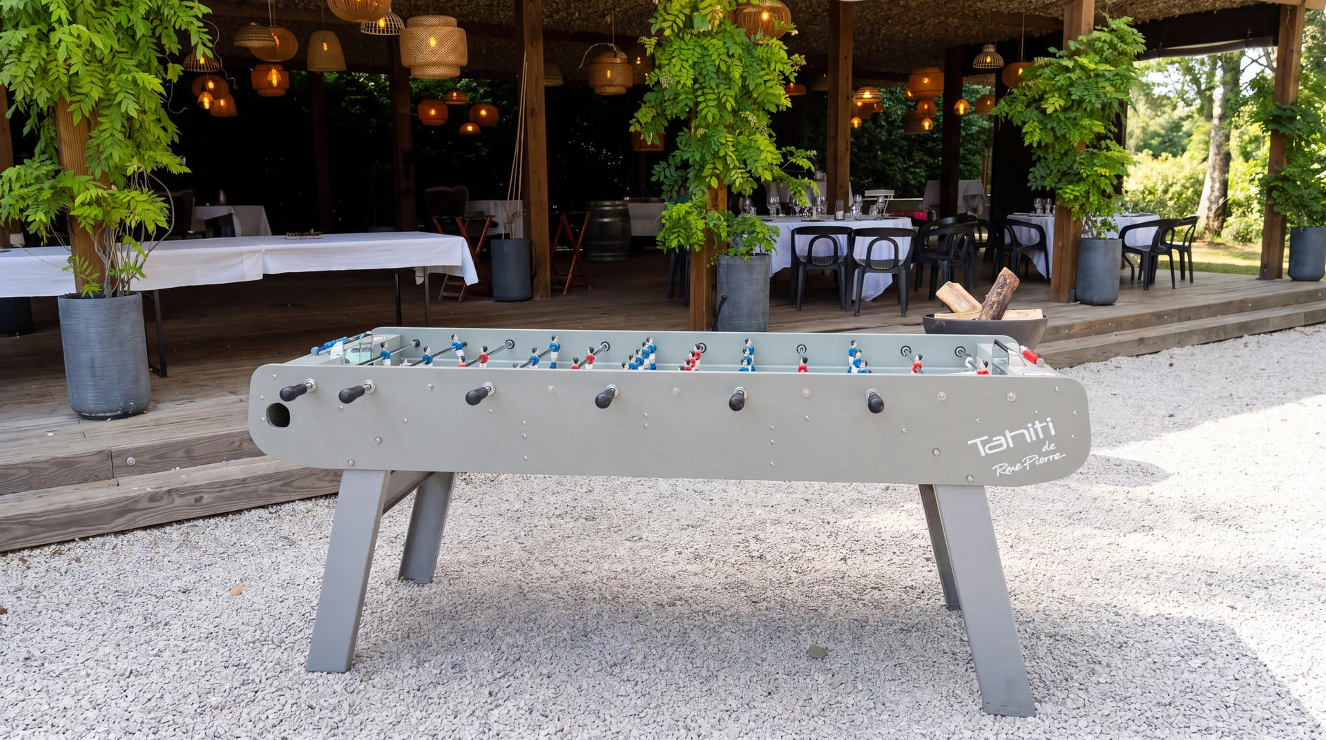 Babyfoot "Tahiti de RoePierre" gris clair, installé en extérieur sur sol de gravier blanc